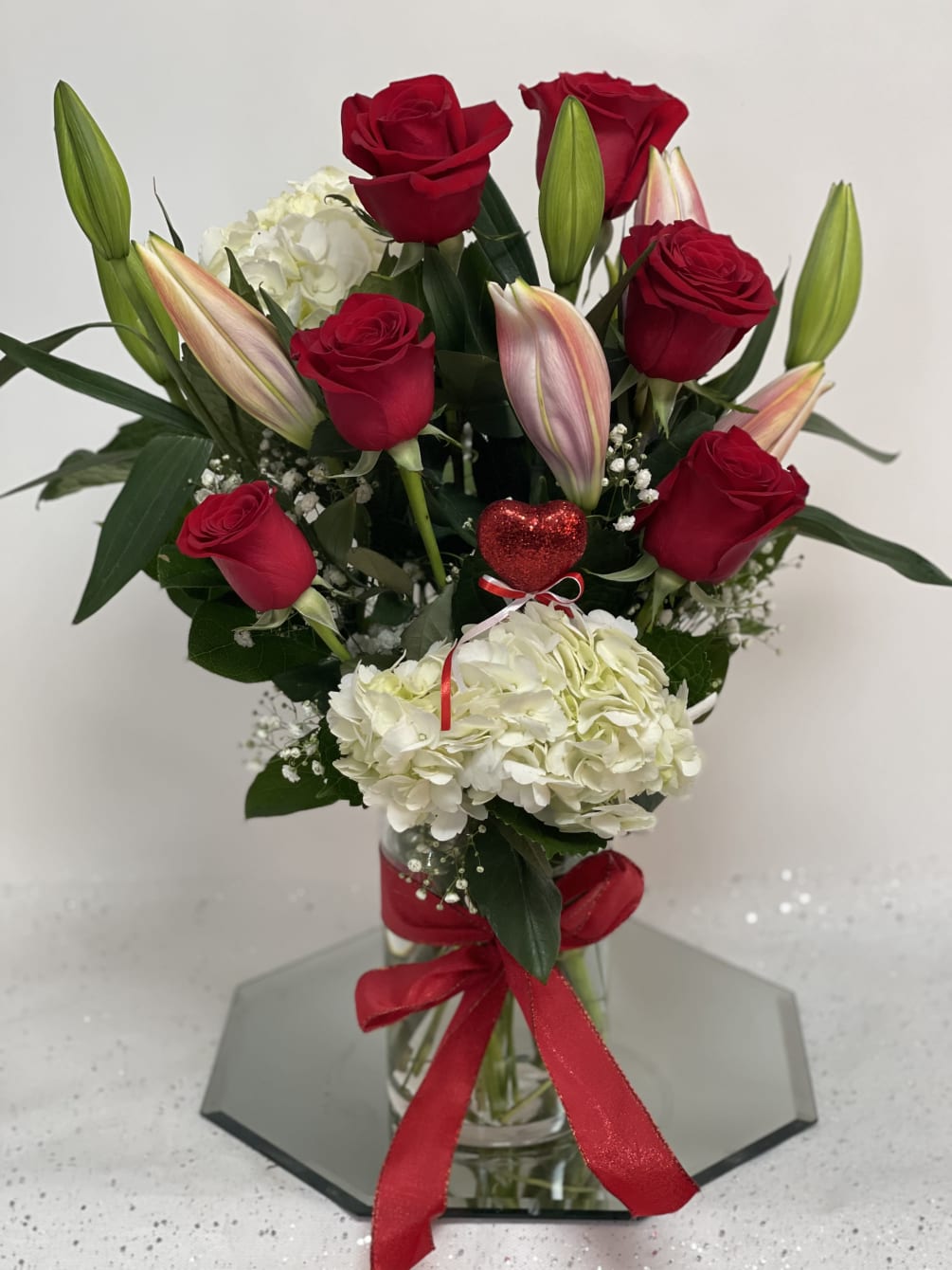Roses, Lilies, and a Hydrangea in a glass vase with a red
