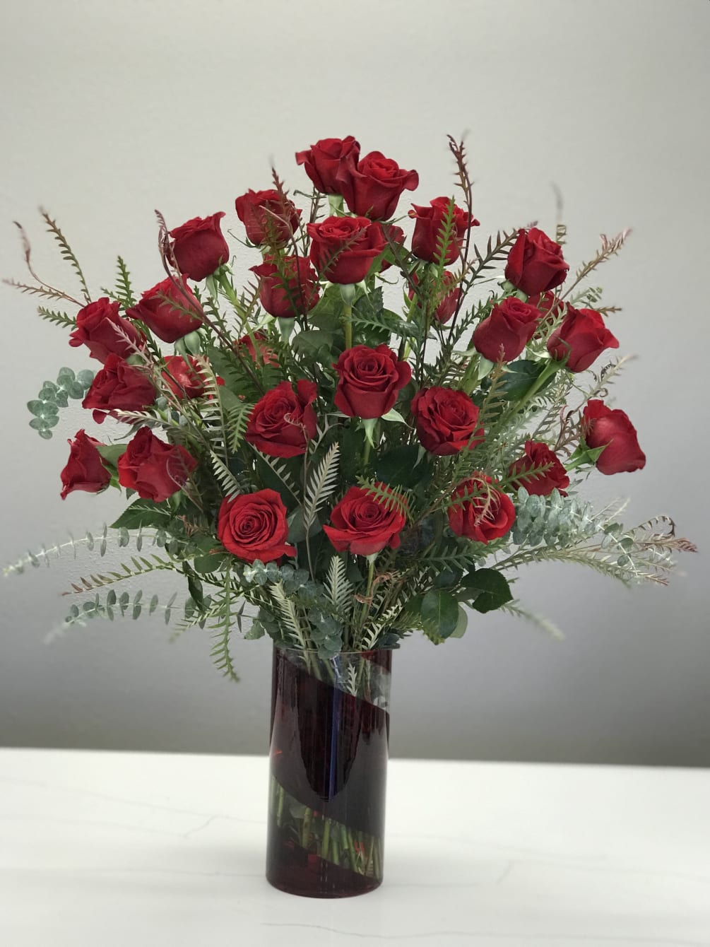 3 dozen long-stemmed red roses arranged in a tall red and clear