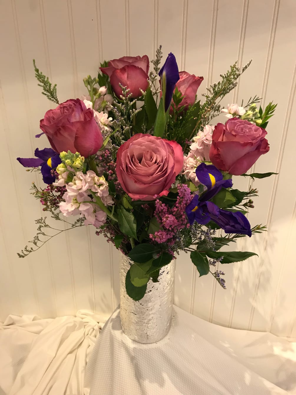 A classy silver vase filled with lovely lavender roses, stock, purple iris