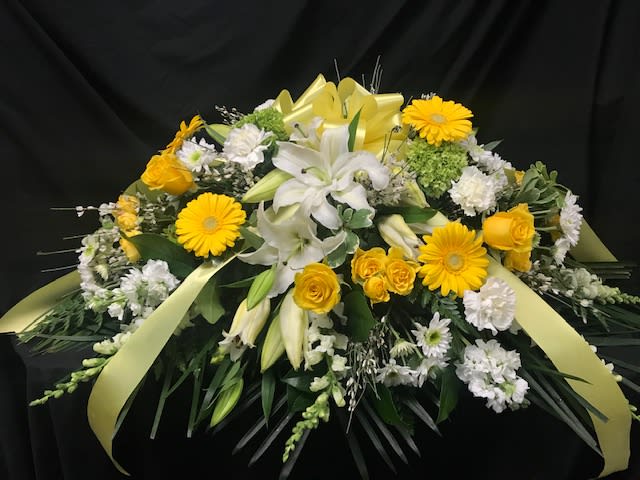 Beautiful casket spray arranged with yellow and white flowers. 
