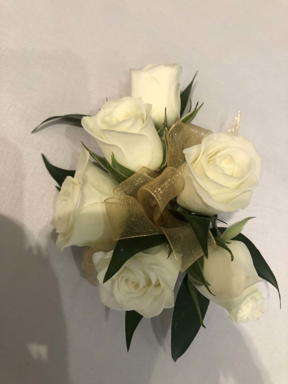 White roses, ribbon and greens for pin on or for on a