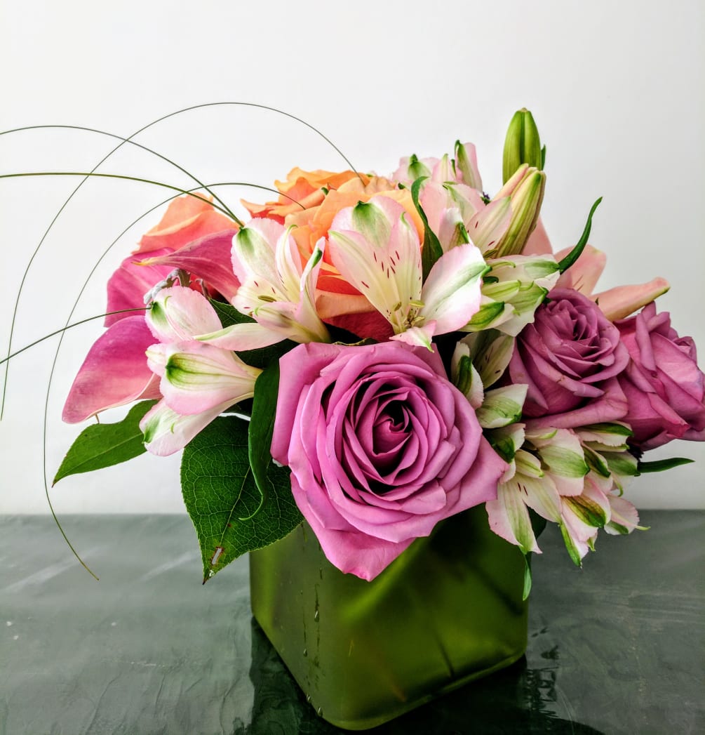 A delightful mix of fresh flowers including three purple Roses, three variegated
