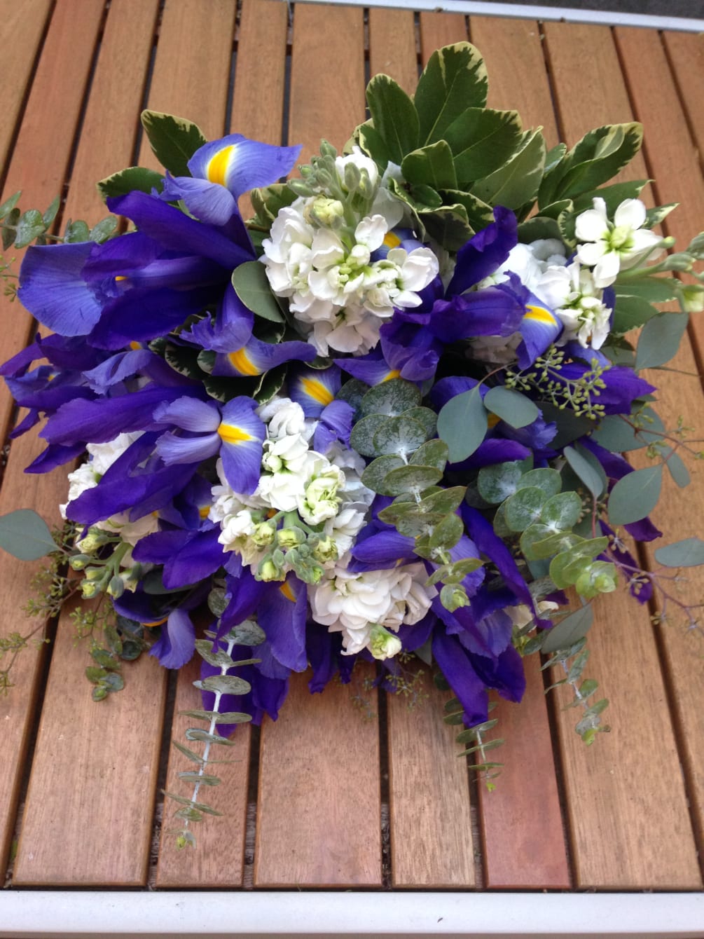 A burst of blue irises, white stock, and seasonal greenery - something