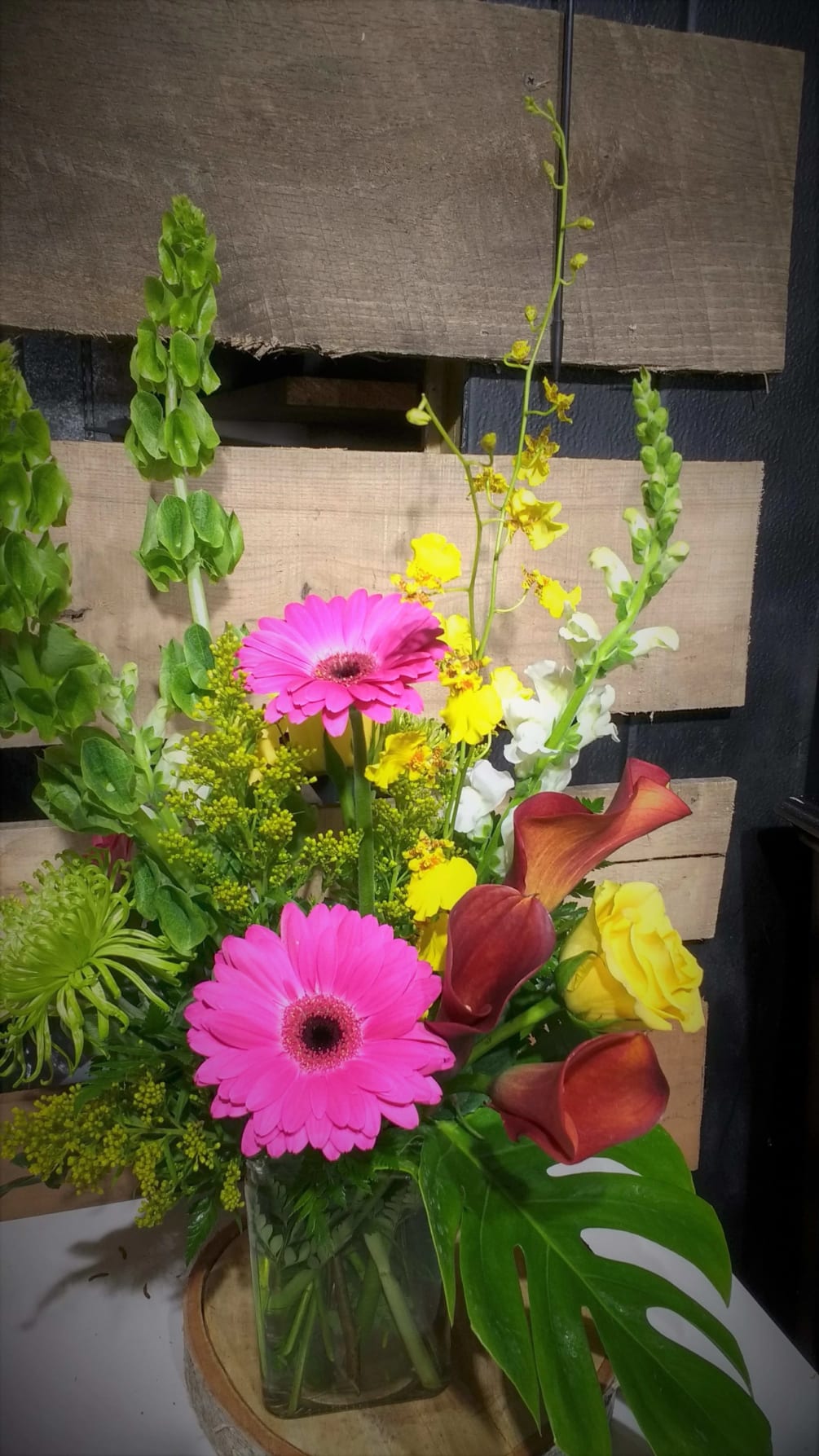 One sided arrangement with bells of Ireland, Gerber daisies, mini calla, snap
