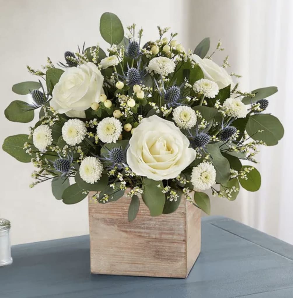 All-around arrangement with white roses, limonium and button poms, cream hypericum and