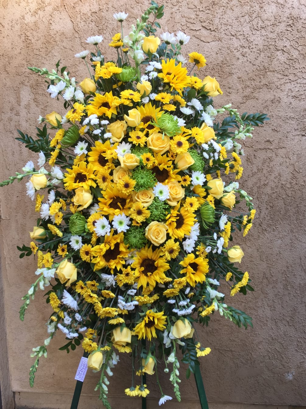 Funeral spray with white and yellow flowers.