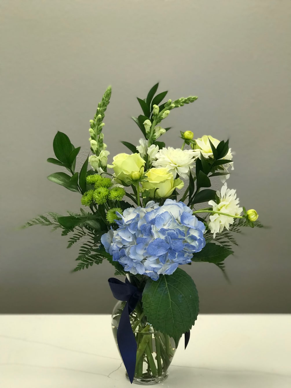 Shades of green and ivory float above a center stage blue hydrangea.
