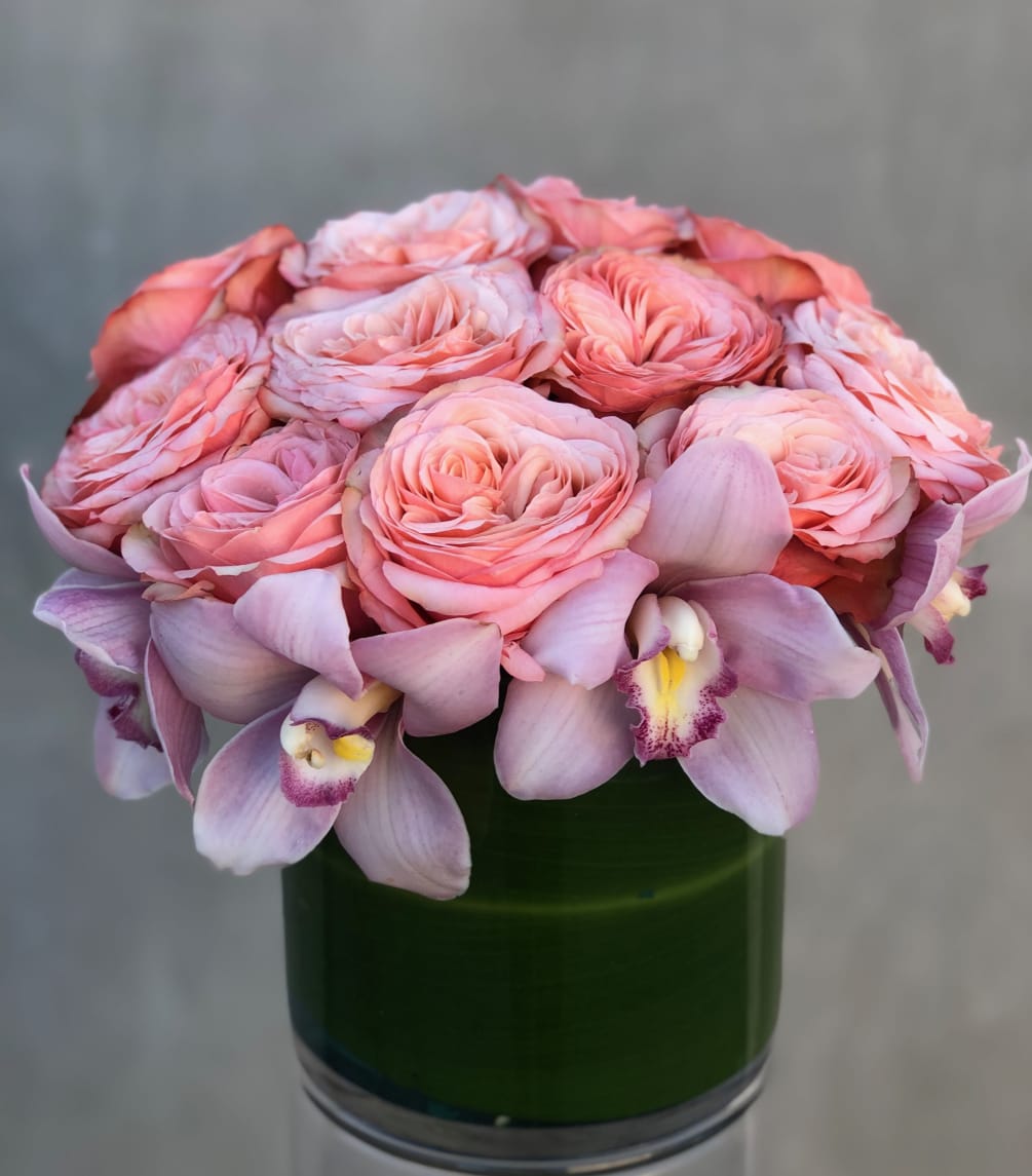 A beautiful collection of blush garden roses and cymbidium orchids in glass