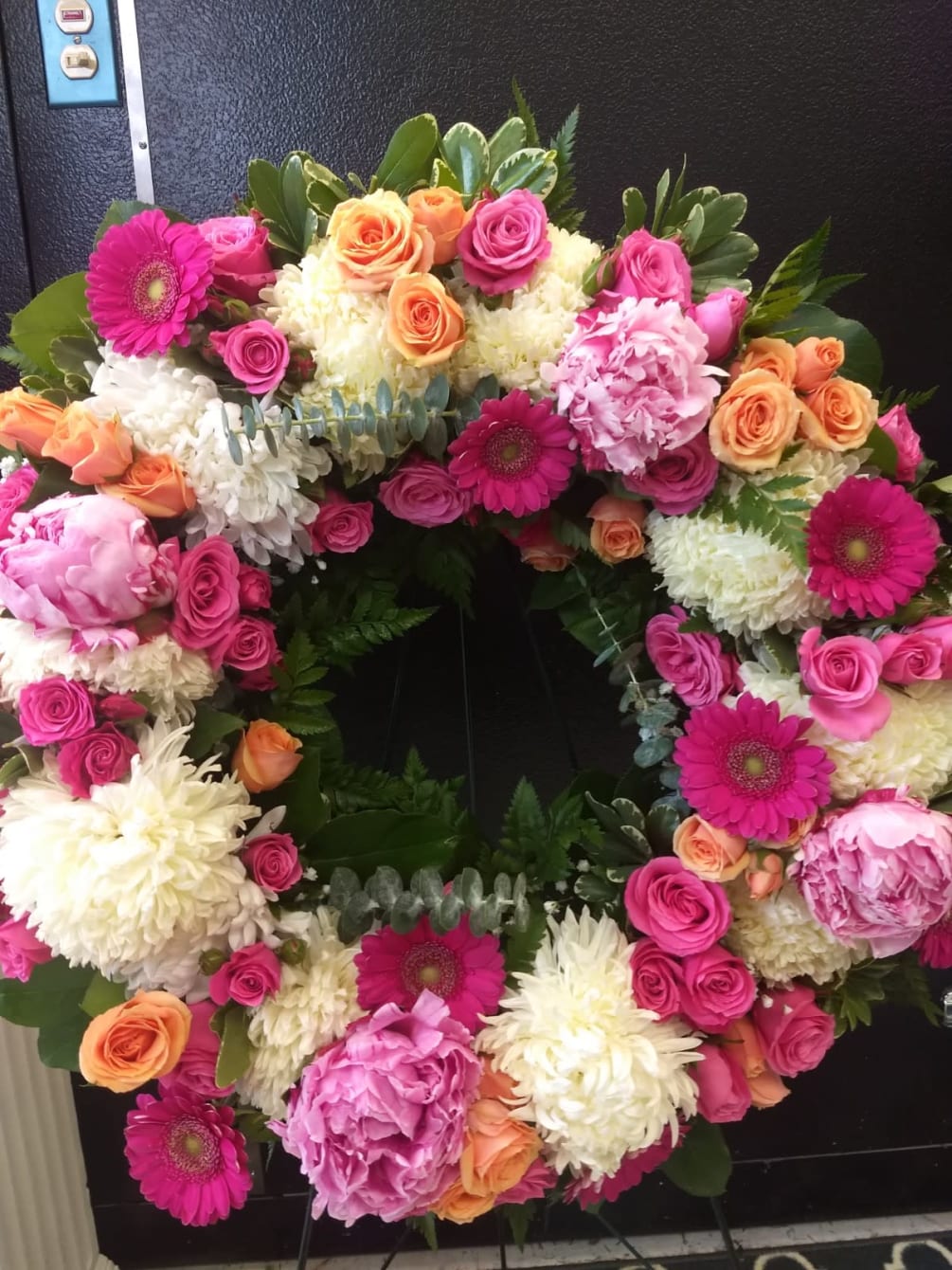 Honor with a beautiful wreath composed of our bright mix florals including