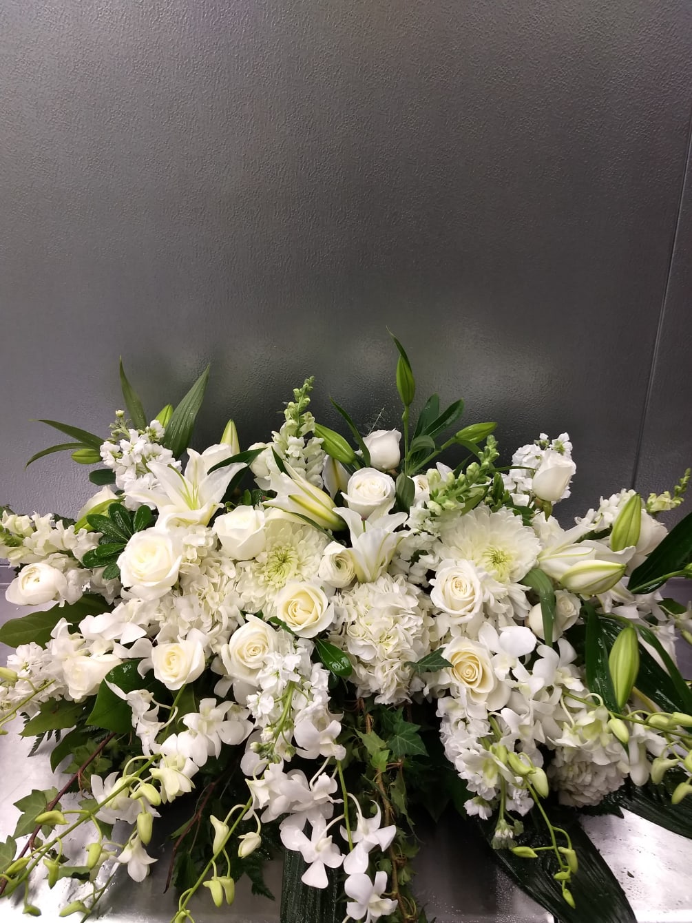 This elegant all white Casket Spray is overflowing with beautiful fragrant Lilies