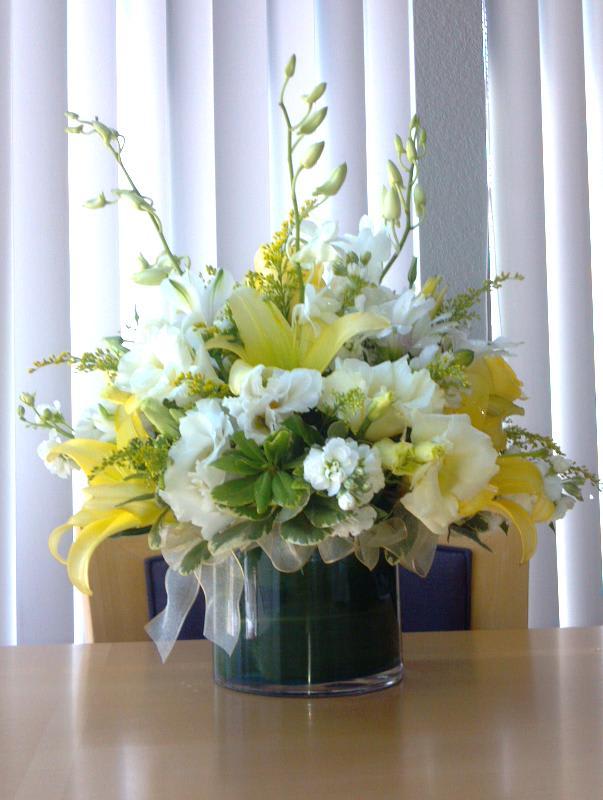 This delicate centerpiece includes Lilies, Lisianthus, Roses, Stock, &amp; Orchids nestled in