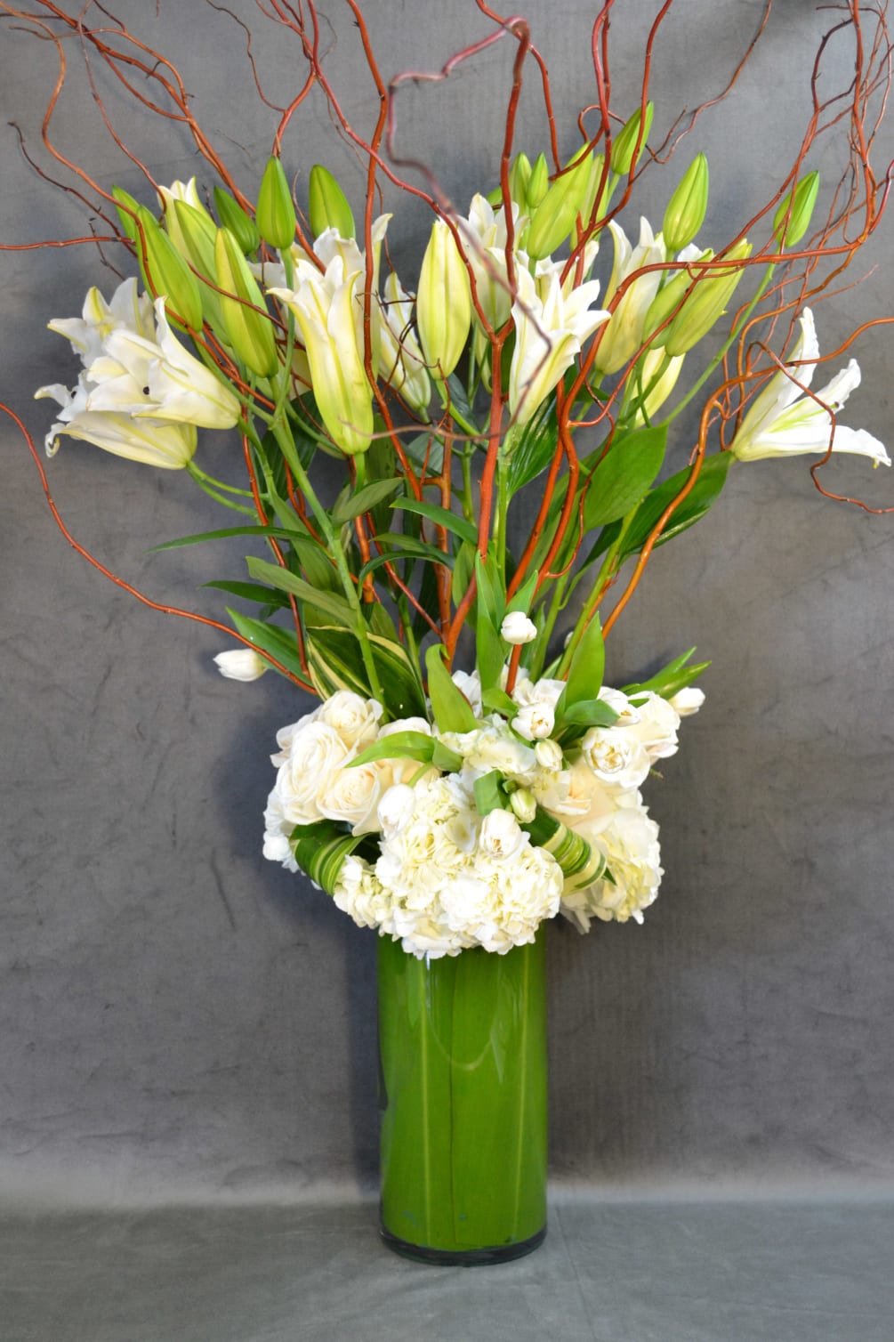 Tall clear vase with Lilies, roses, tulips and hydrangeas. 