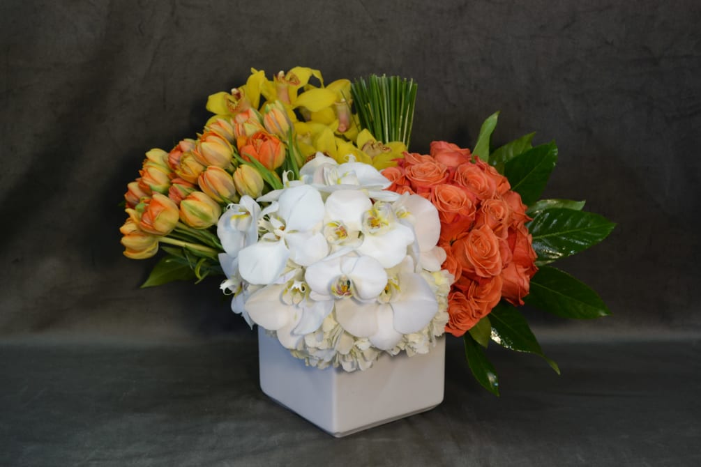 Tulips, Cymbidium Orchids, Roses, Phalaenopsis Orchids in a ceramic white vase.
 