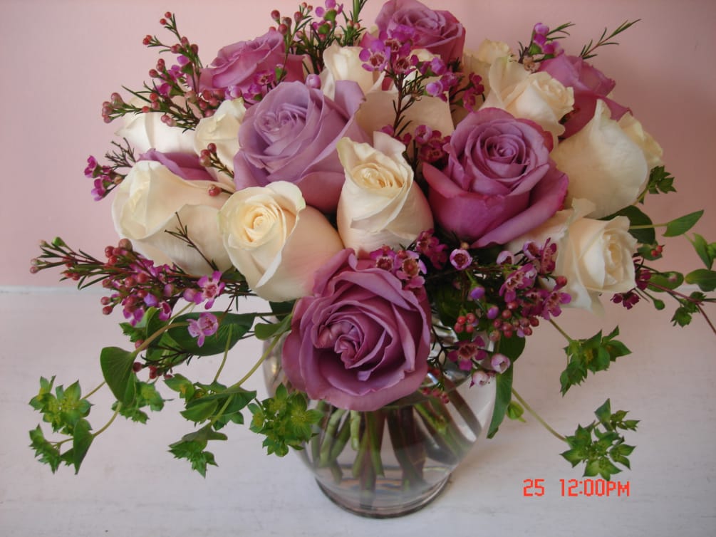 Lovely Lavender and pure White roses are arranged in clear glass vase