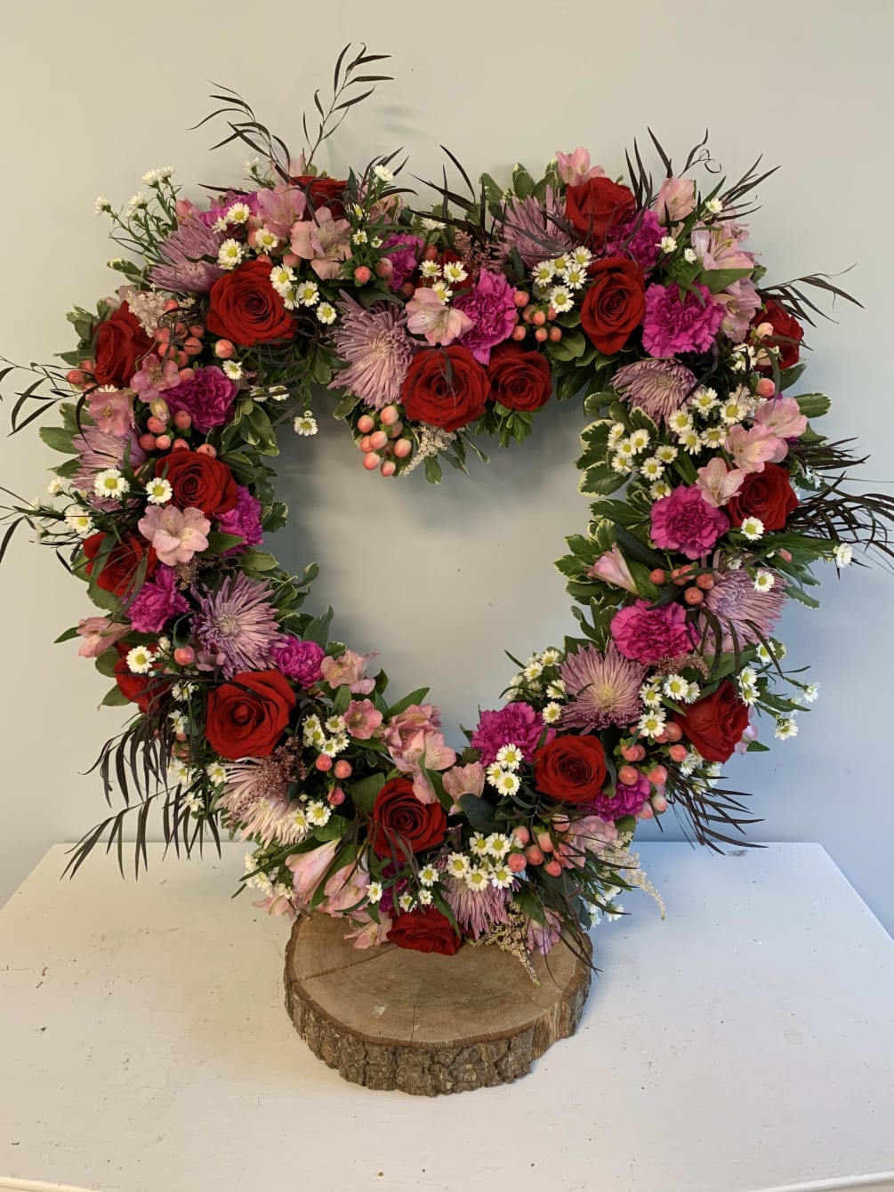 This large open heart wreath is filled with purple,red,pink flowers