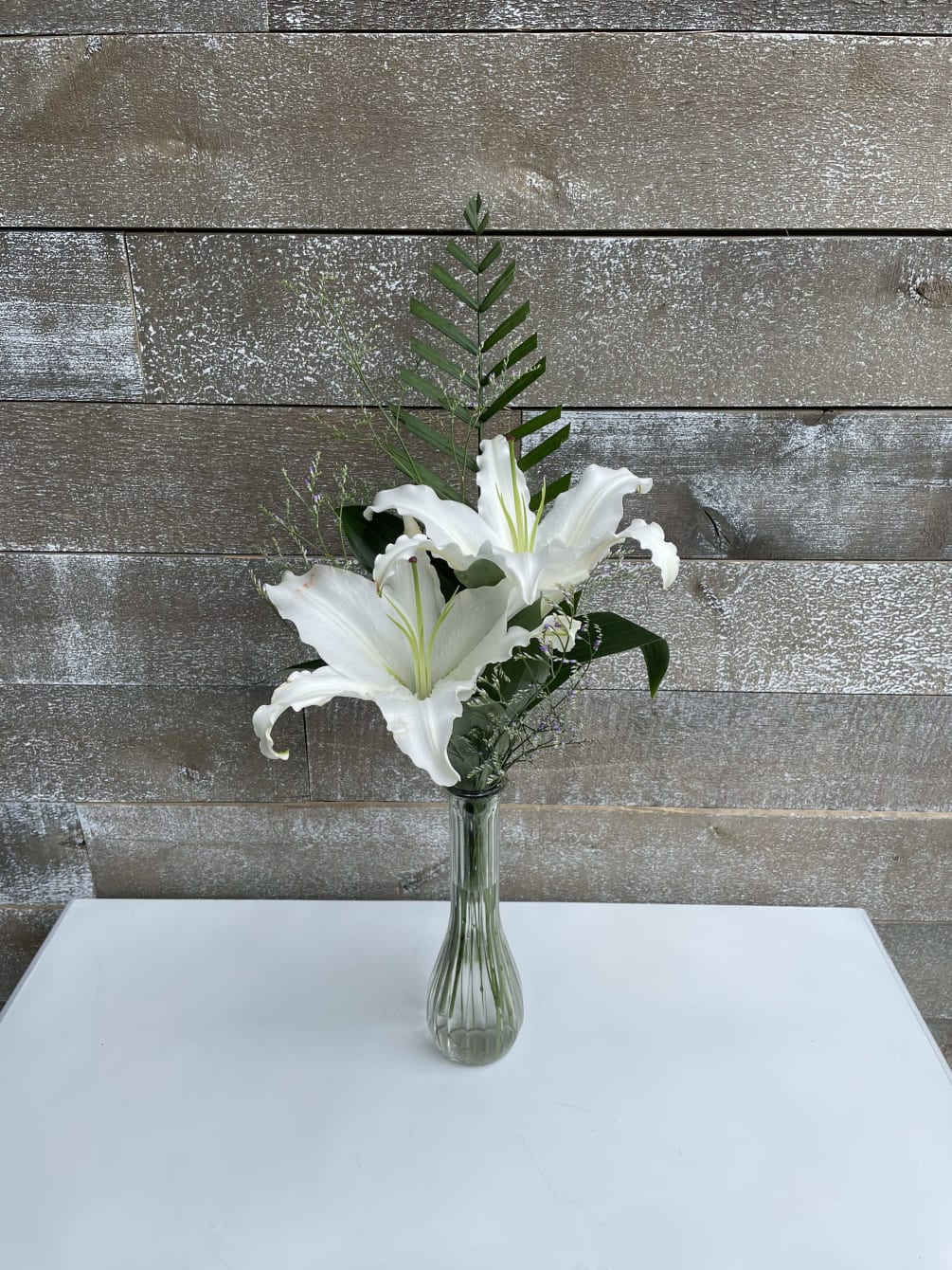 A simple single stem stargazer with greens and filler. 