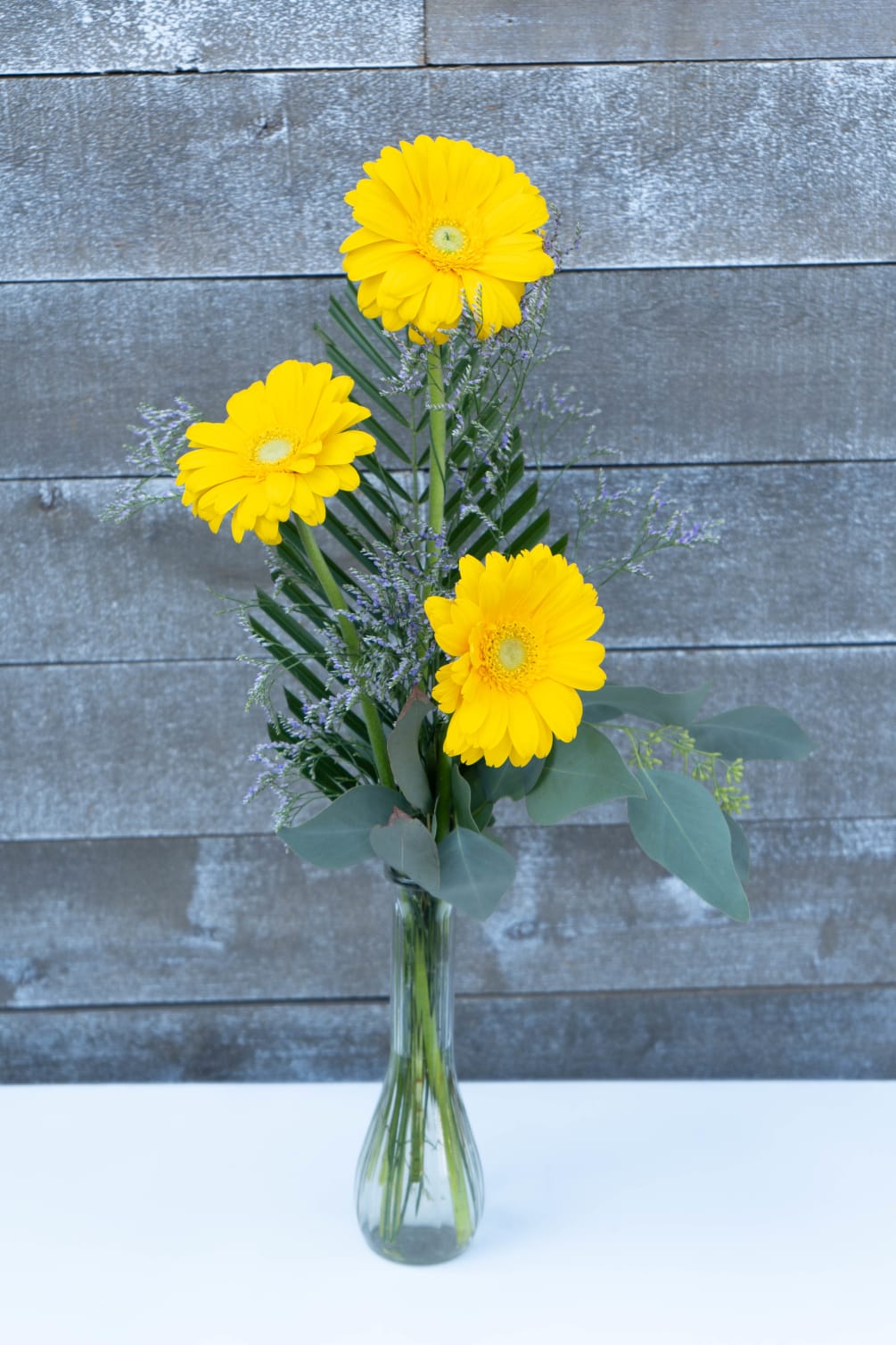 Classic gorgeous yellow Dutch gerbera daisies complimented with Greenery and light filler.