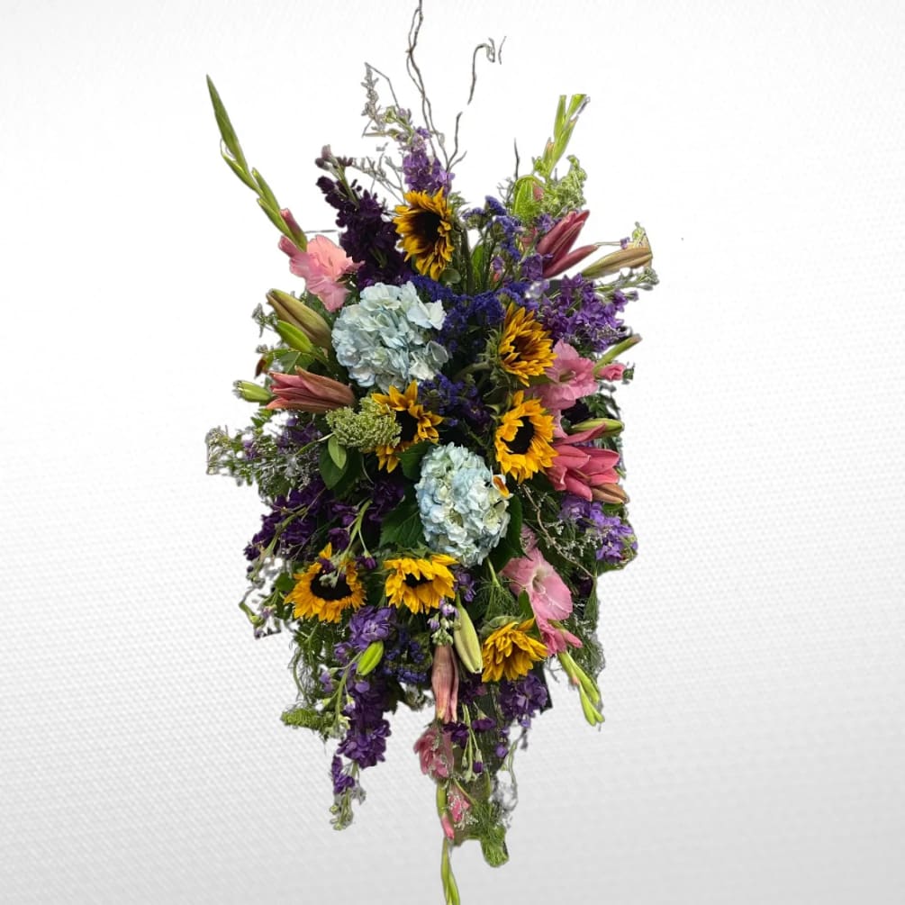 A standing spray with sunflowers, hydrangeas, gladioli, stock and queen Anne&#039;s lace.