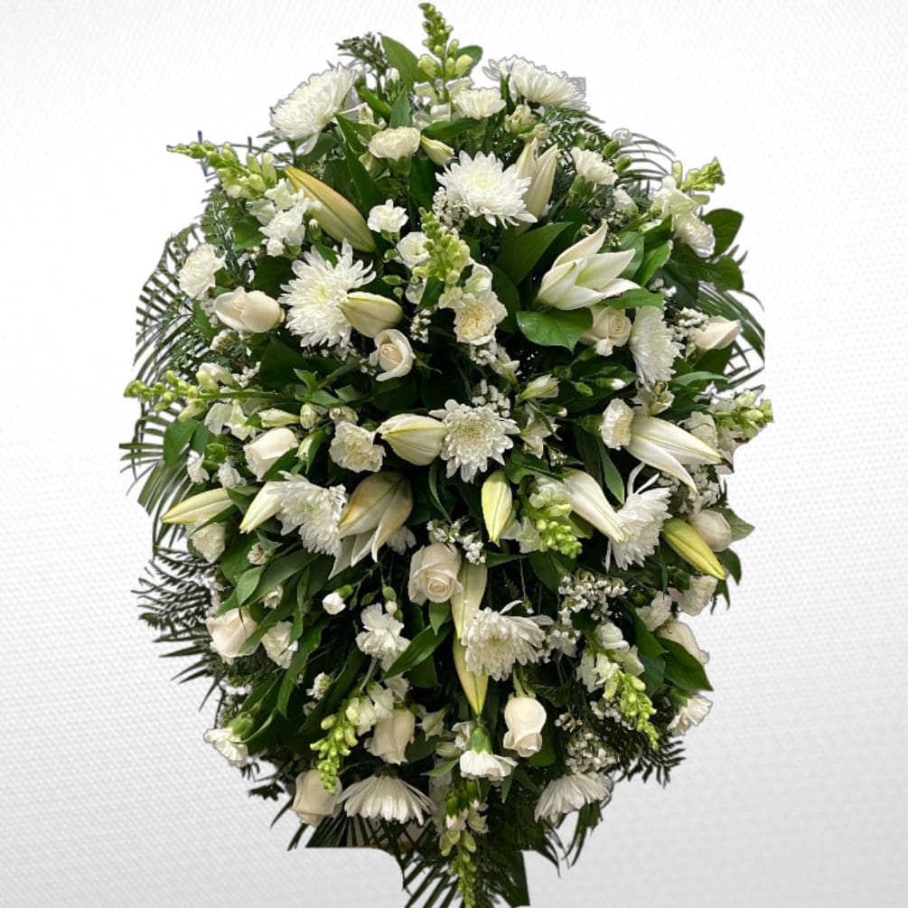 An all white standing spray of white disbuds, roses, snapdragons, carnations and