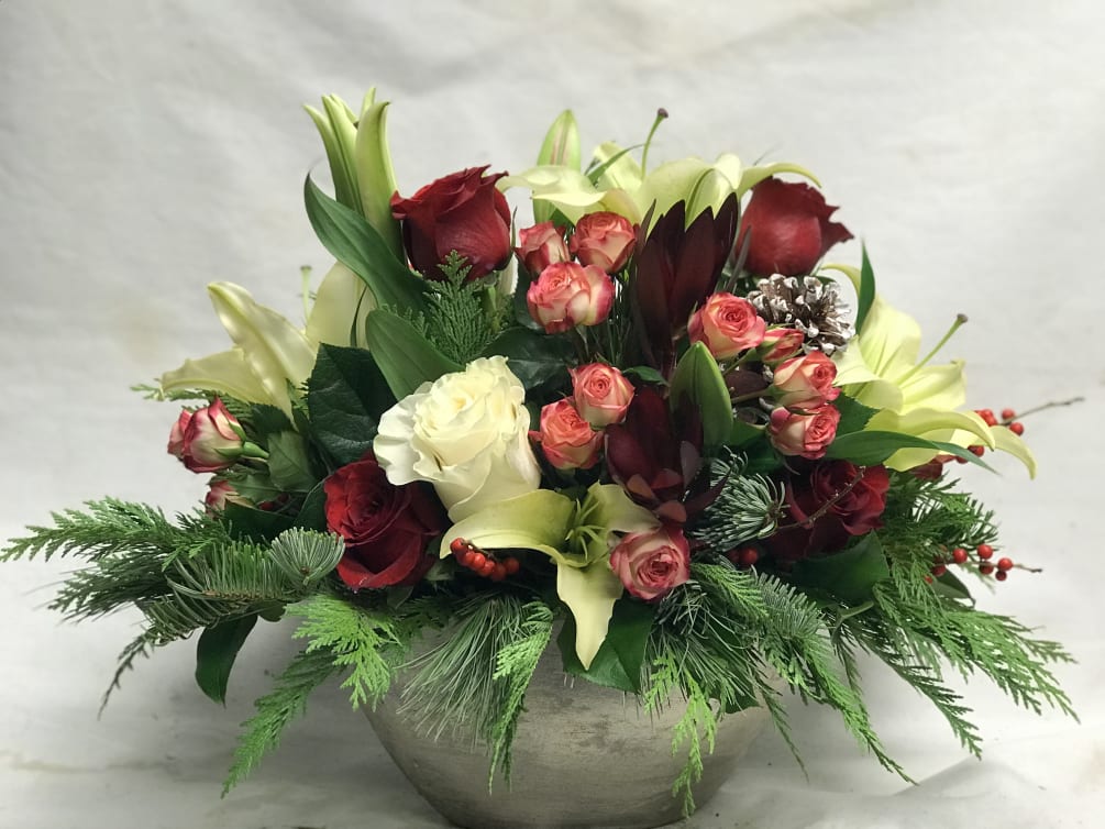 Holiday greens with roses, lily , leucadendron and novelty accents designed in