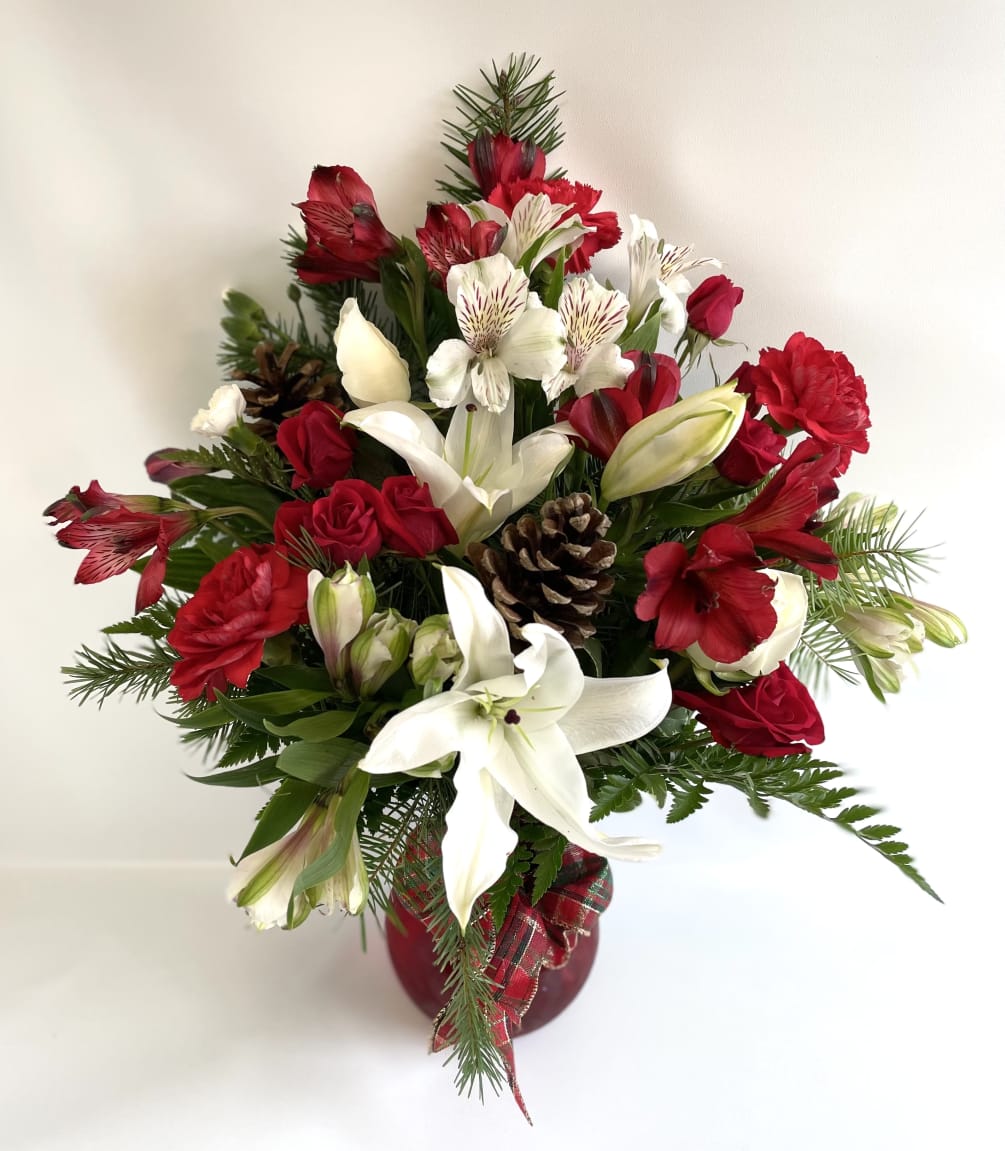 A red vase filled with traditional colors of Christmas. Lilies, Roses, Carnations