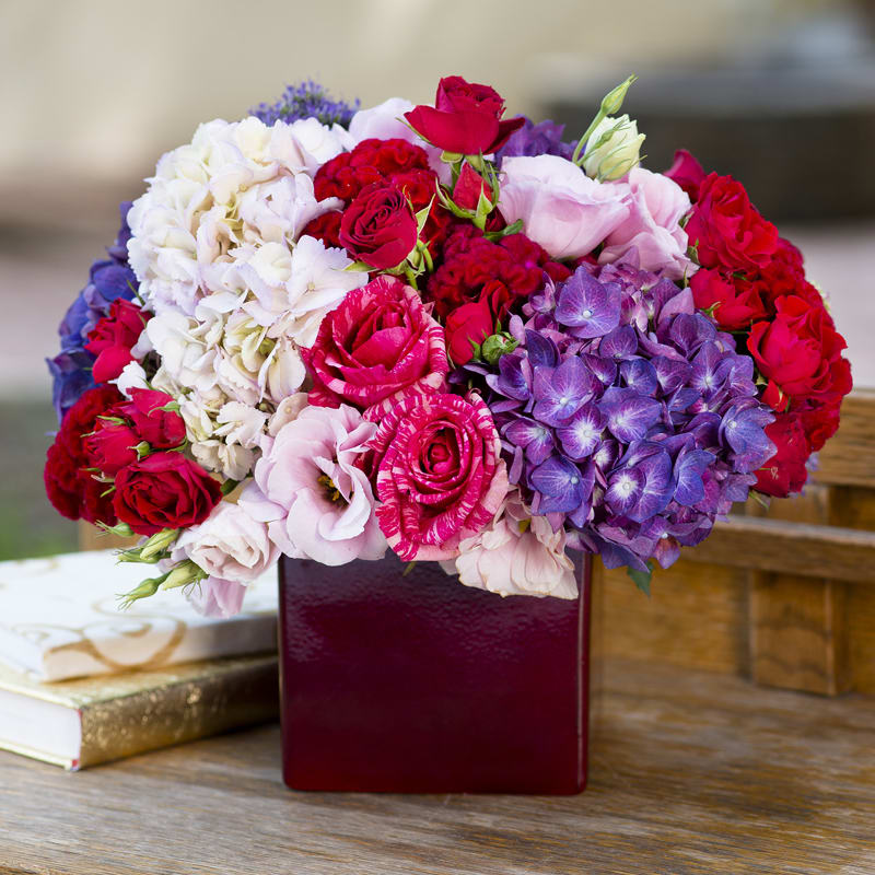 Burgundy vase filled with blush, purple hydrangeas, hot pink roses,  pink