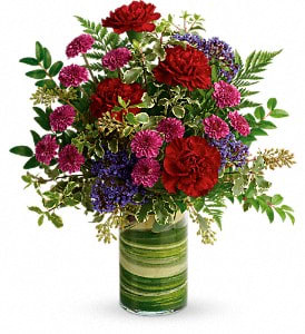 A vase with long lasting, mixed jewel toned flowers and assorted foliages.