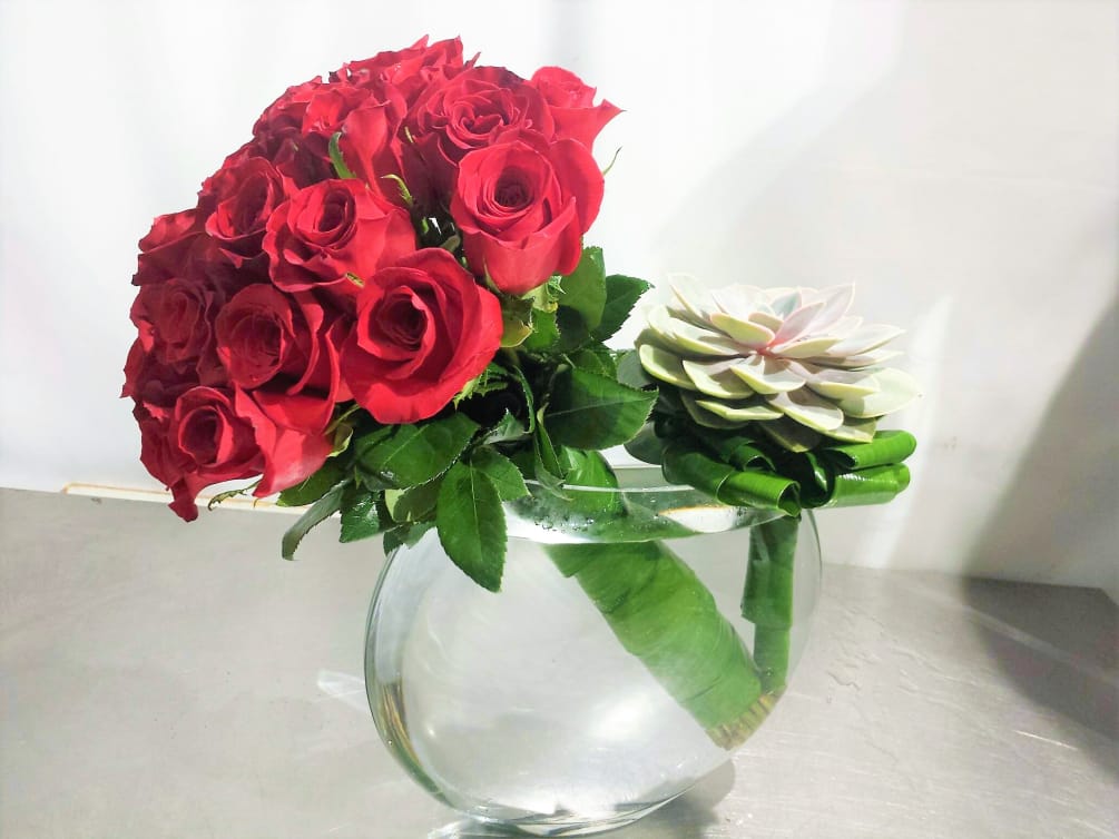 A modern red rose arrangement in a contemporary flat glass bowl with