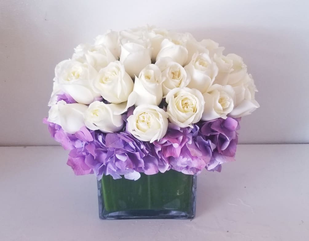 Elegant and clean low and lush arrangement composed of purple hydrangeas surrounded