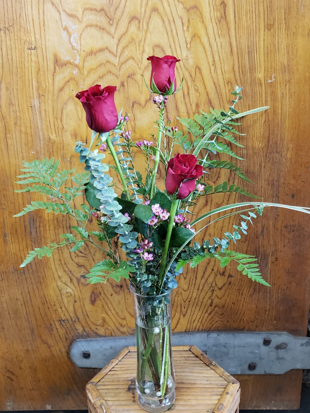 A trio of roses with fragrant spiral eucalyptus and waxflower presented in