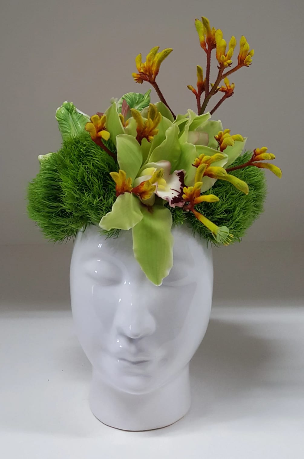 A modern design using green dianthus, orchids, kangaroo paw along with parrot