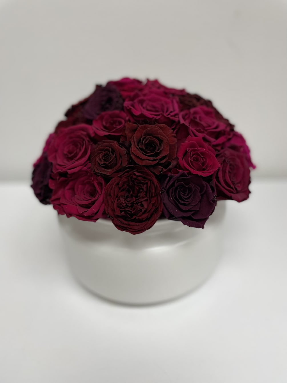 Red and pink colored preserved roses in a white ceramic vase. 8.25&rdquo;