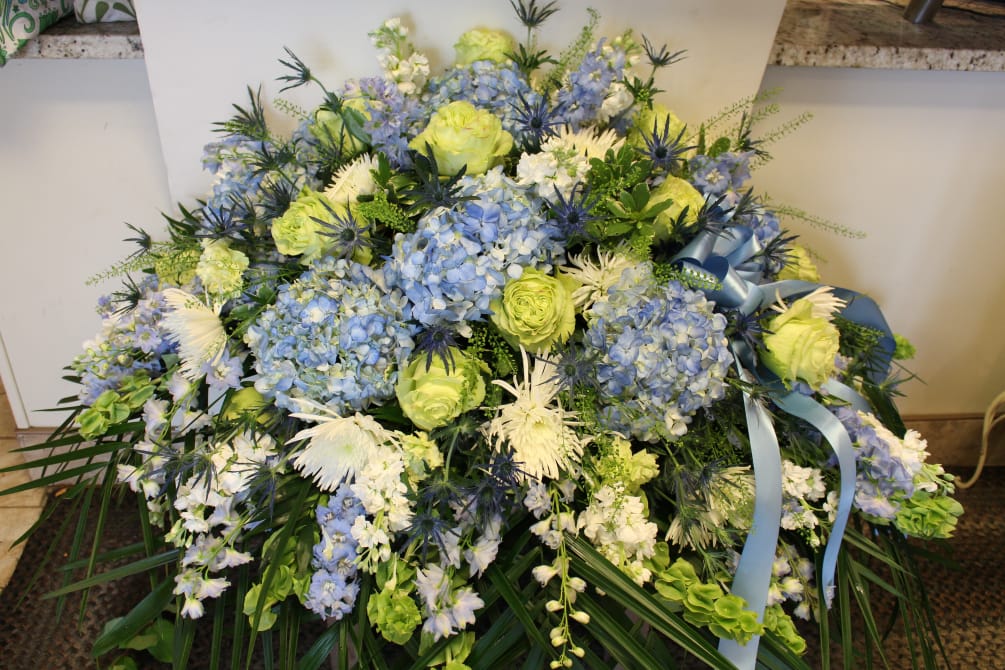 Blue hydrangea, green roses, thistle in a beautiful spread for a casket