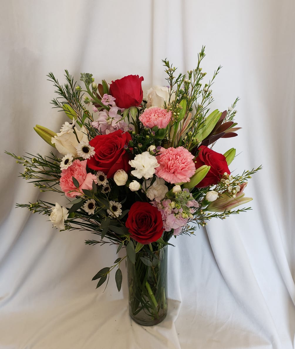 Feminine and pretty floral arrangement with roses, lilies, and stock.