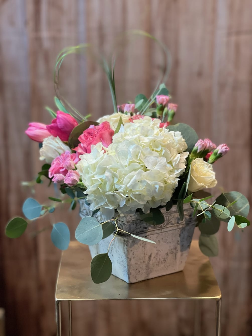 An elegant vintage style vessel filled with hydrangea, lavish garden roses, tulips