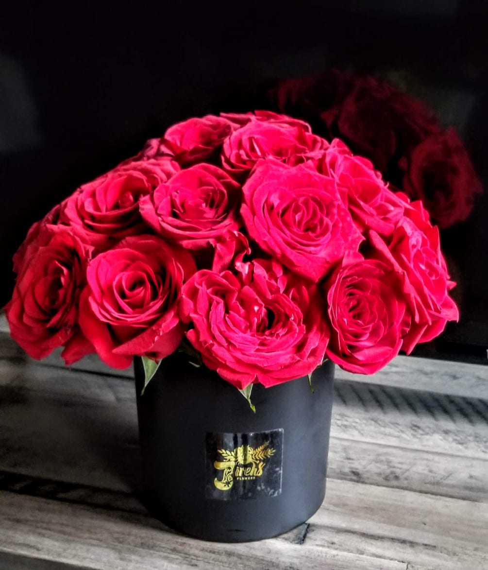 A gorgeously elaborate bouquet with red Roses in an elegant black vase.