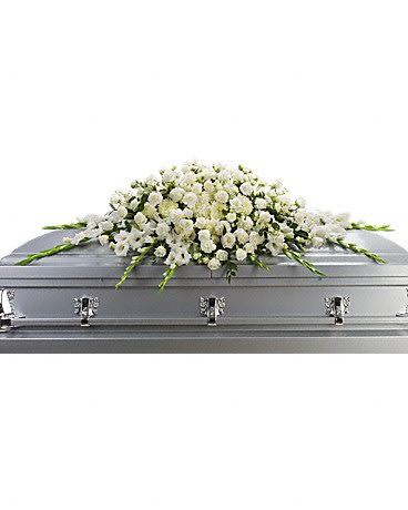 A blanket of snow-white flowers gracefully placed on the casket is a