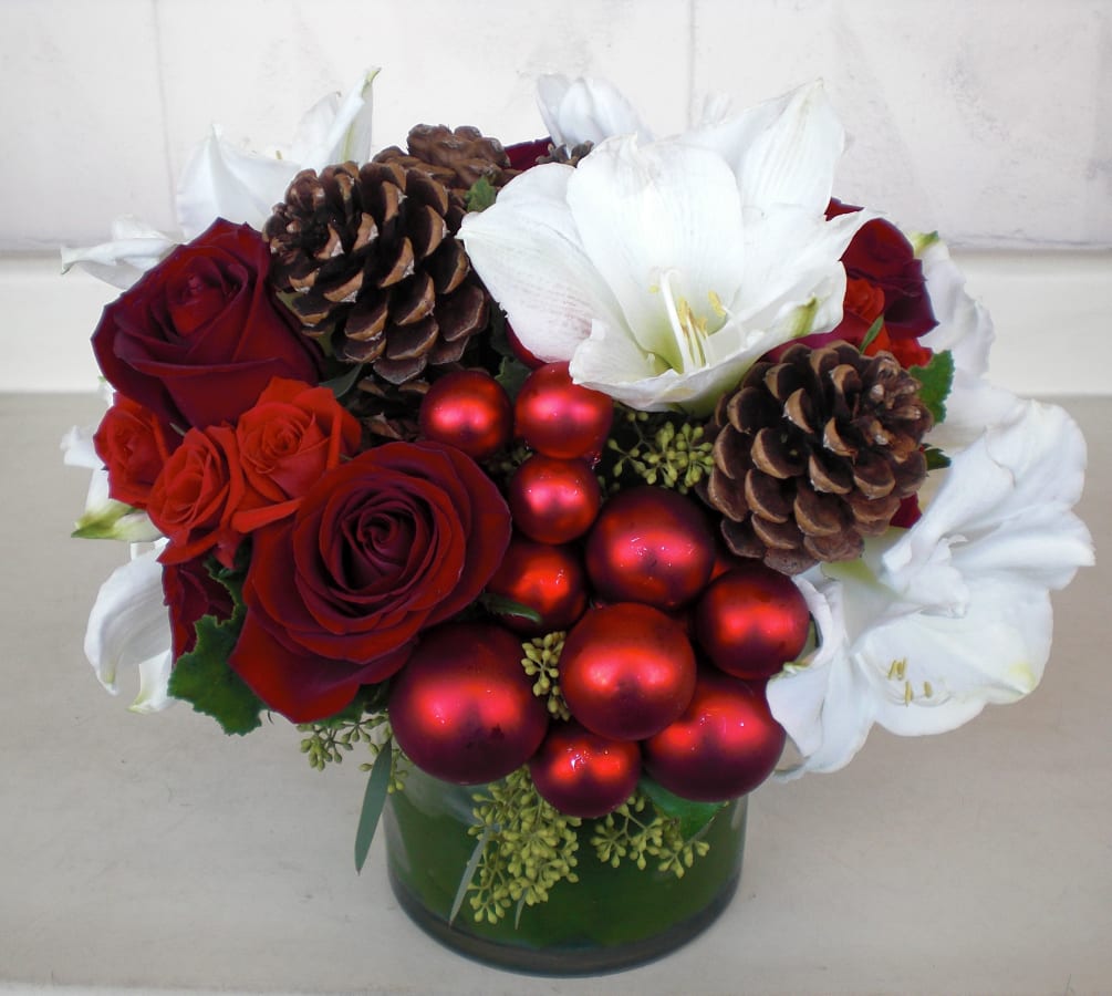Beautiful winter arrangement with amaryllis, red roses, pine cones and ornaments delicately