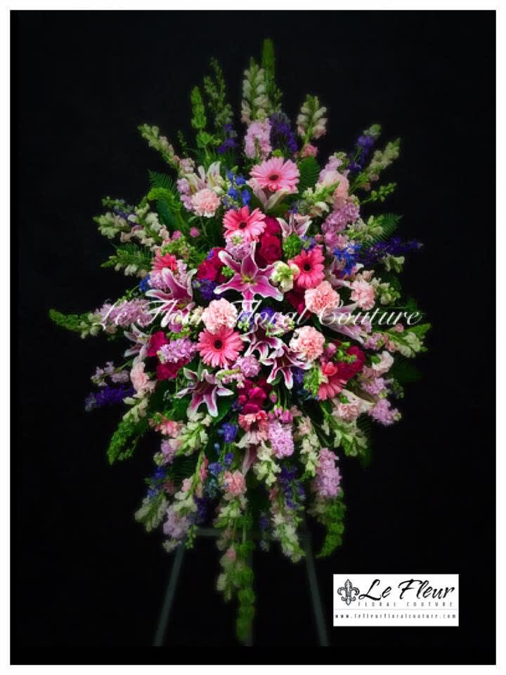 A tall standing spray of gladiolus, bells of Ireland, roses, gerbera daisies