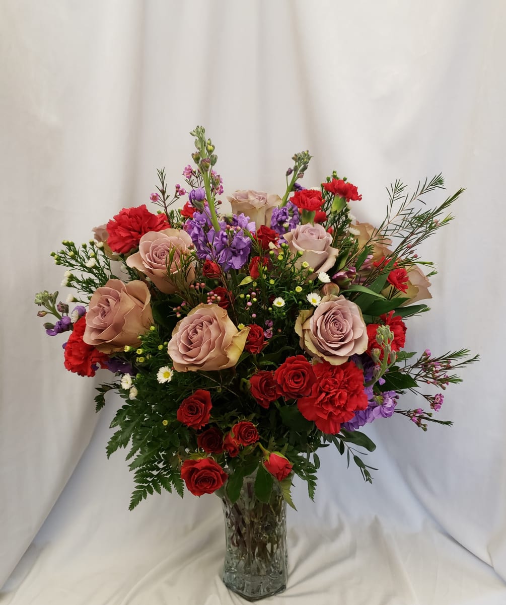 Stunning array of purple roses, red spray roses, purple stock, and red