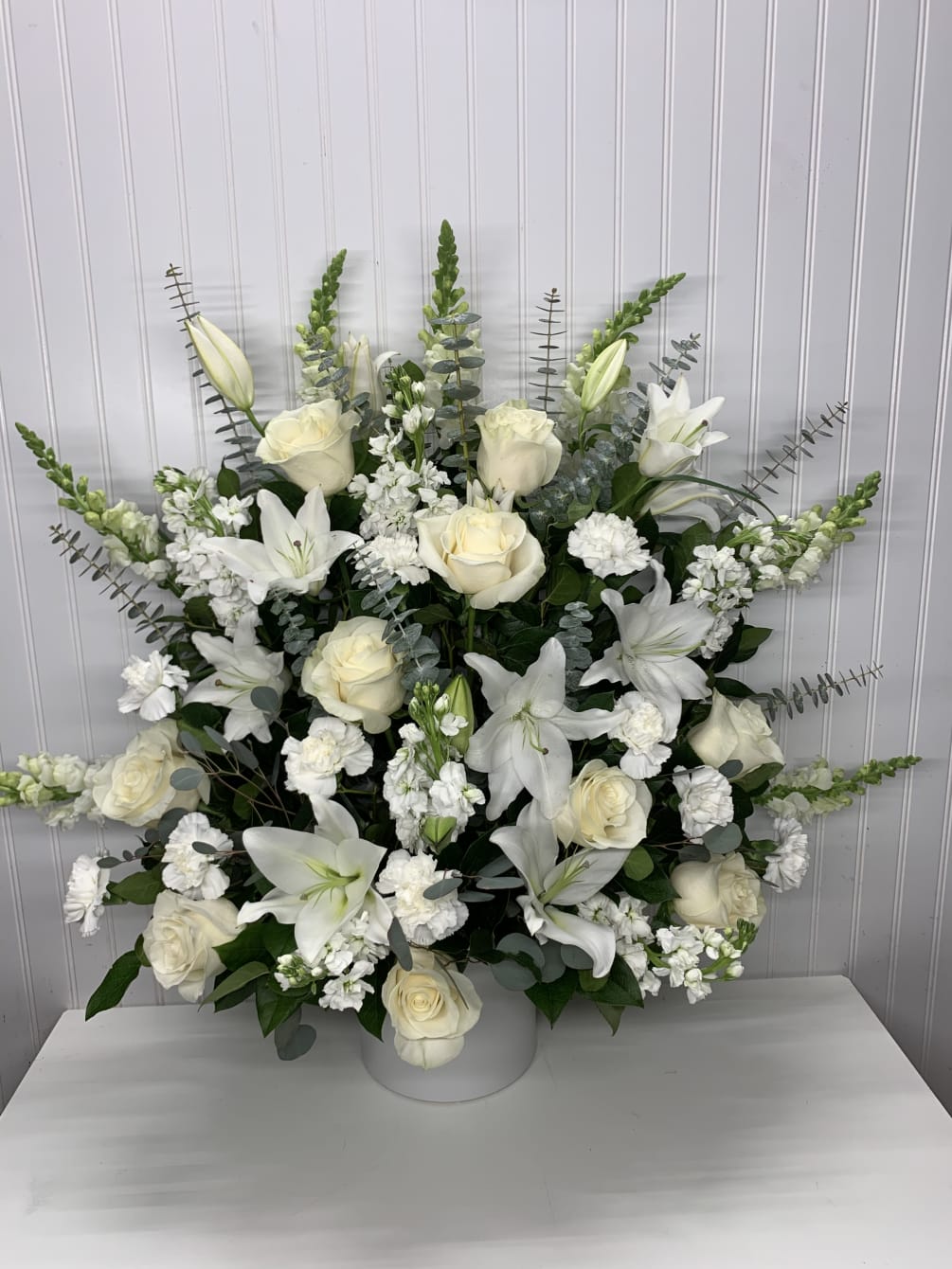 a beautiful floor basket all white whit lilies, roses, stock,  