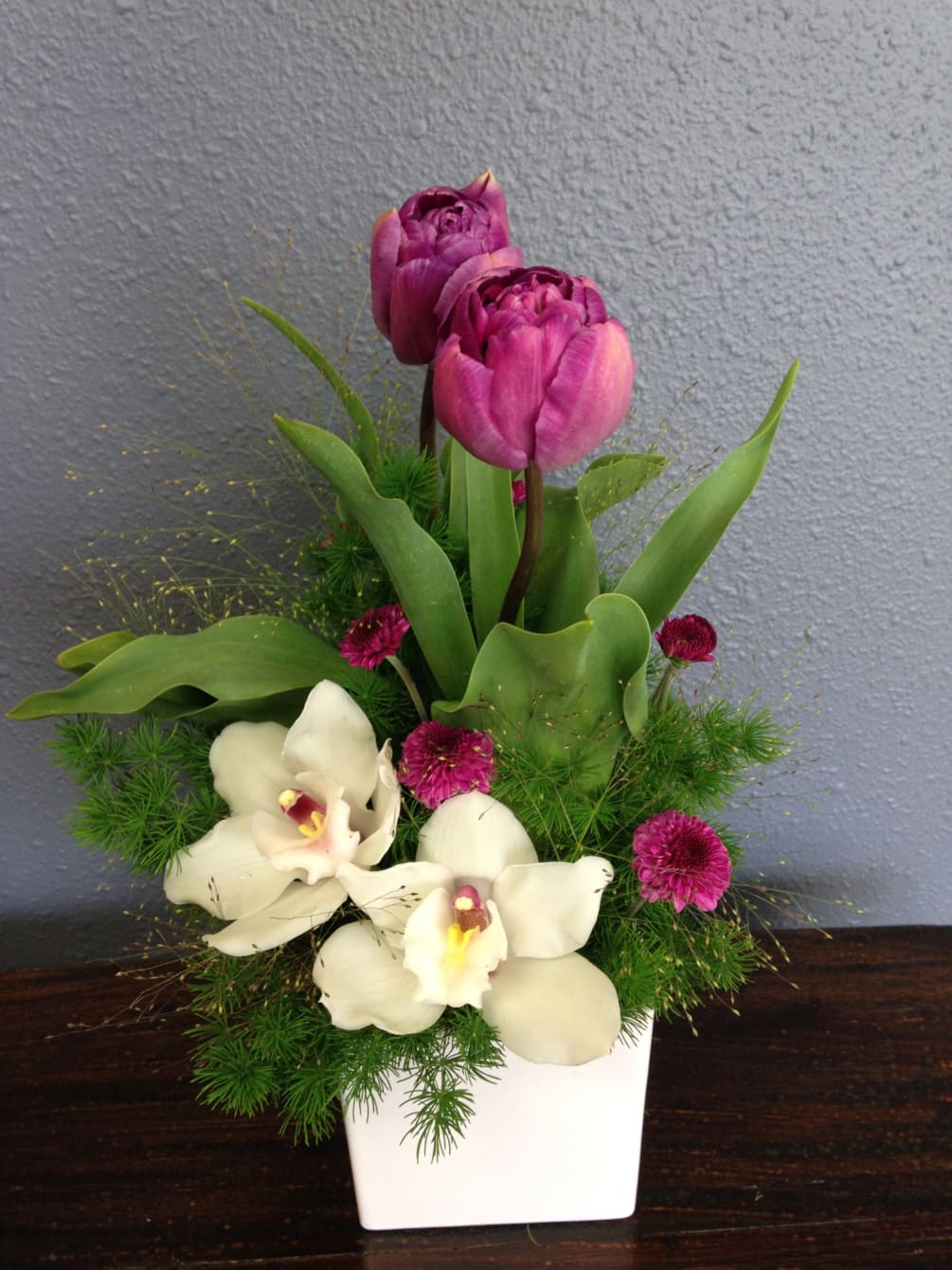 Cute arrangement with Tulips, Orchids with explosion grass in a ceramic vase