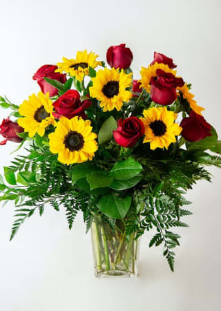 This arrangement has a mixture of yellow sunflowers and red roses. Beautiful