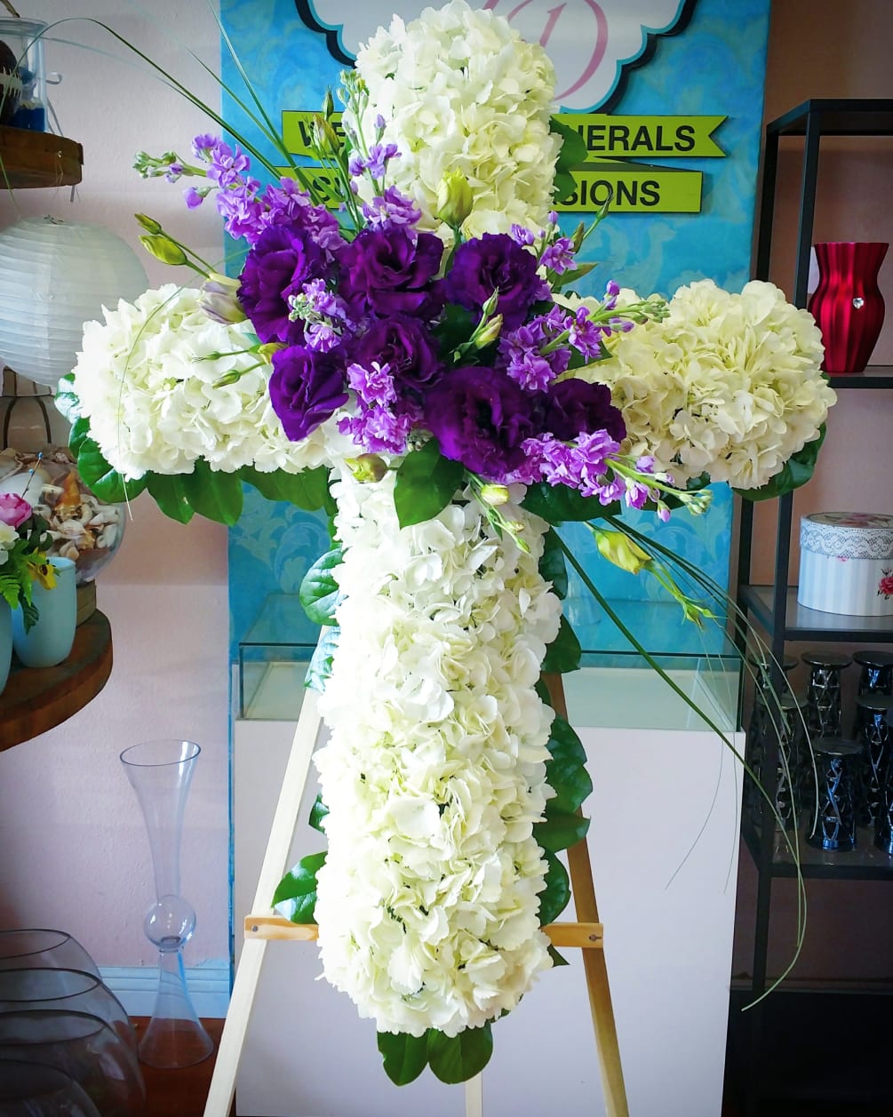 white hydrangea cross with purple lisianthus and lavender stock flowers.