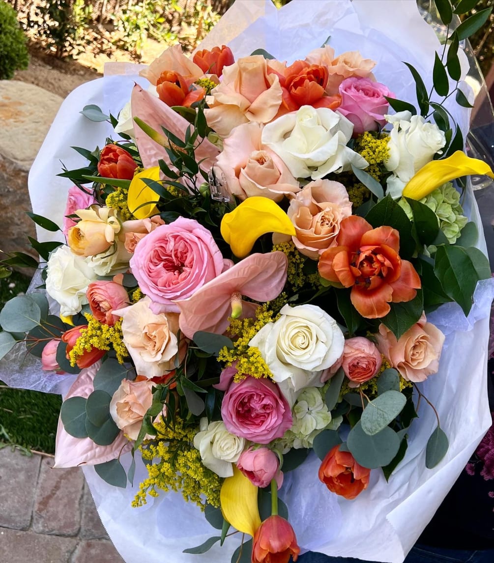 Mixed roses, tulips, ranunculus, calla lilies, hydrangea wrapped a presentation bouquet.