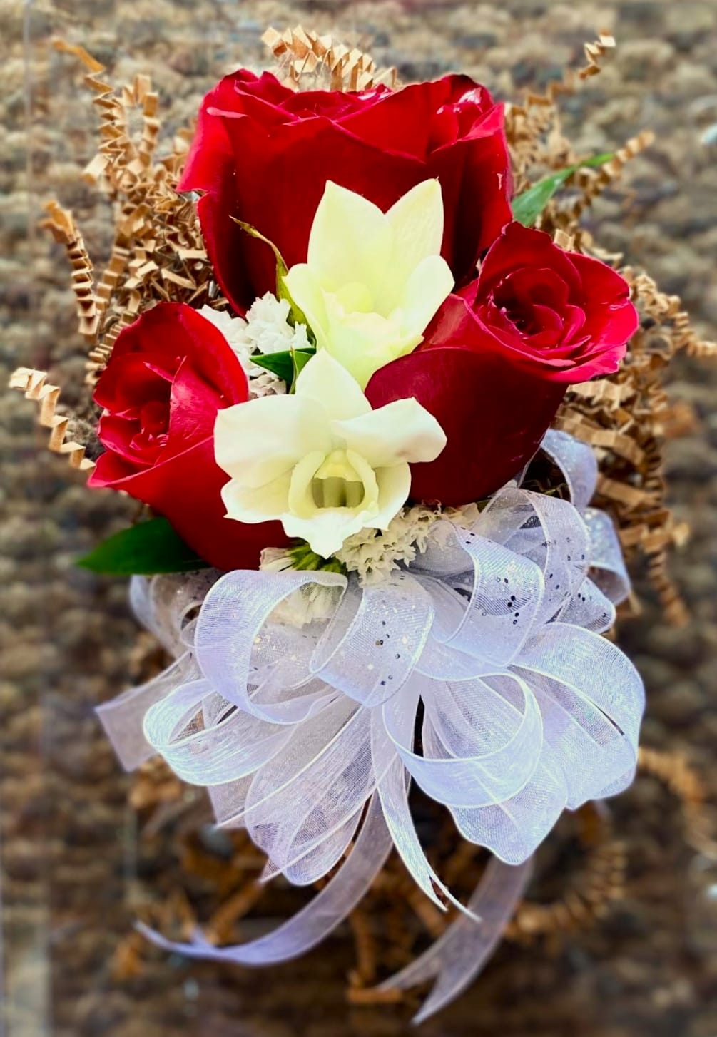 This classic pin corsage is composed of three Red Roses, Dendrobium orchids