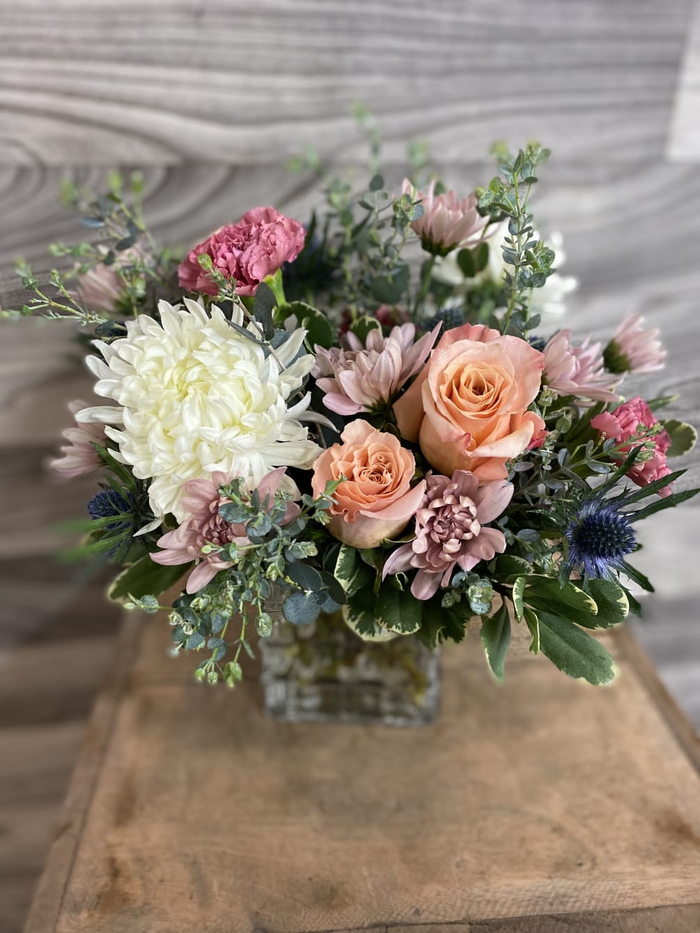 A lush pastel mix, with roses, spider mums, thistle, and carnations. 