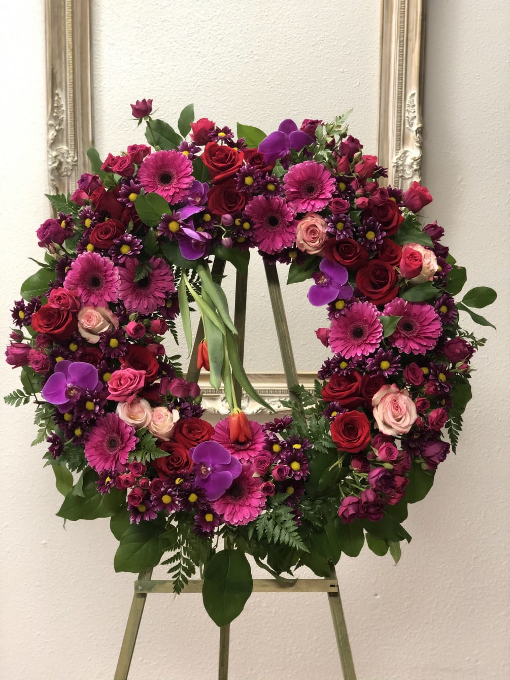Combination of bright color flowers for this funeral wreath makes it stand