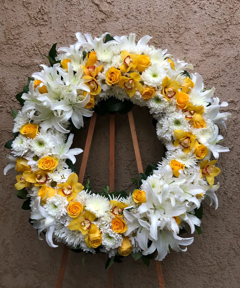 Standing wreath including white and yellow flowers.