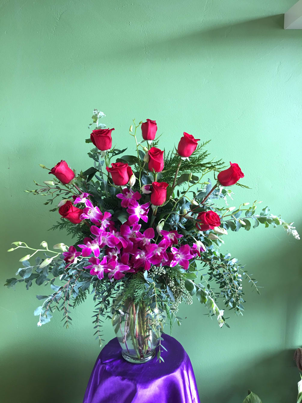 A mix of one dozen red roses with purple orchid.